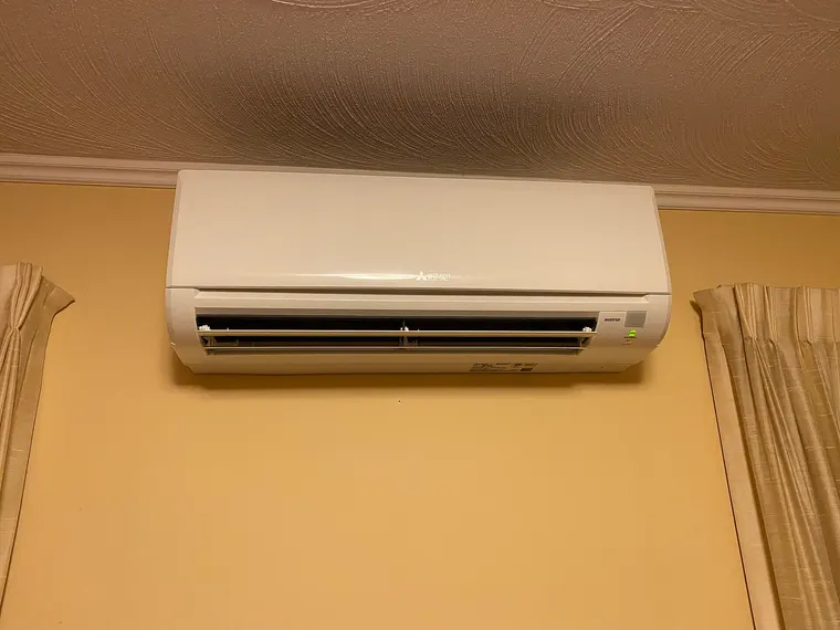 The indoor air handler of a ducted heat pump with its access panel removed, showing the blower and coil.