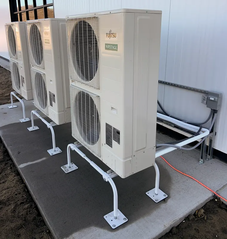 Several heat pump outdoor units installed side by side against a building, serving one property.
